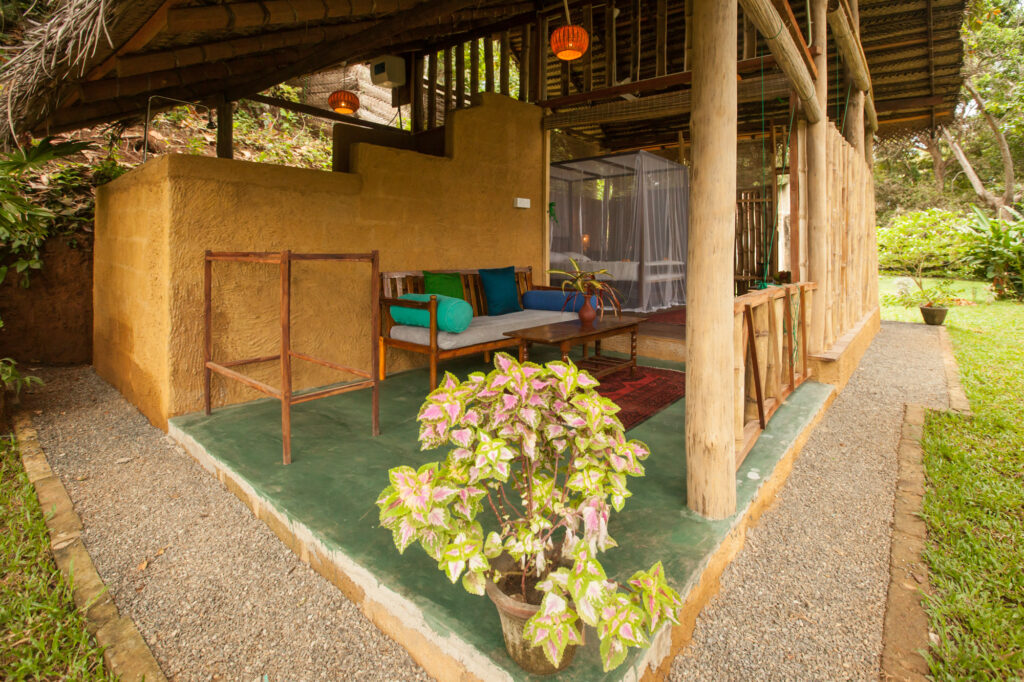 Covered hut veranda with a cushioned daybed and lanterns at Talalla Retreat, Sri Lanka