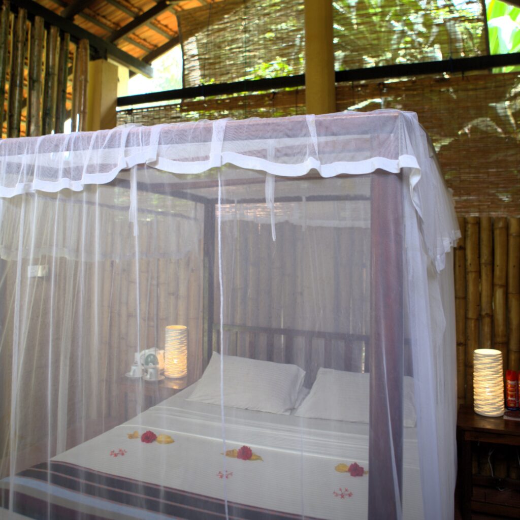 Four-poster bed with mosquito netting inside an open-sided bamboo hut at Talalla Retreat, Sri Lanka