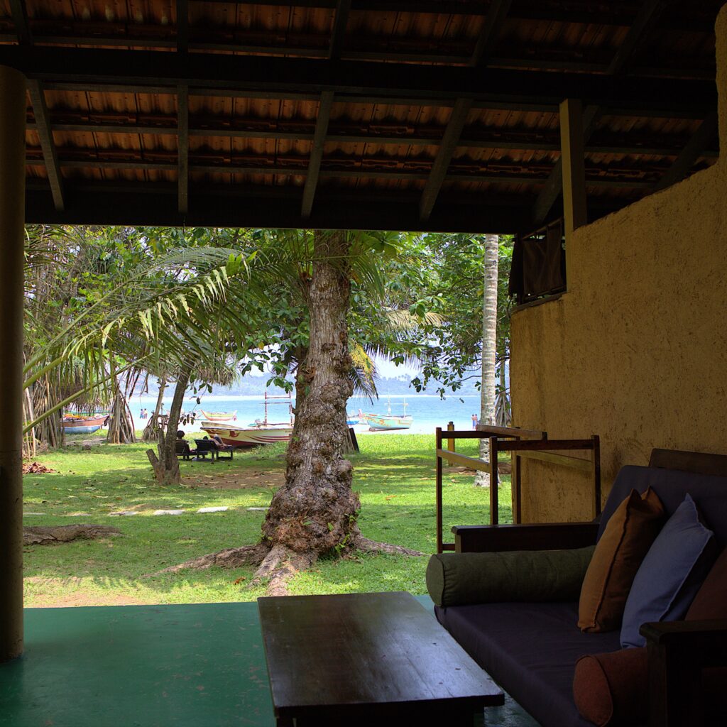 Hut veranda with a daybed looking out to the garden and ocean at Talalla Retreat, Sri Lanka