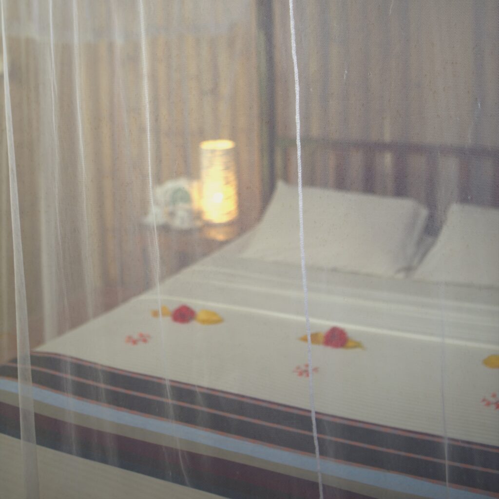 Four-poster bed with flower petals and a candle lantern at Talalla Retreat, Sri Lanka