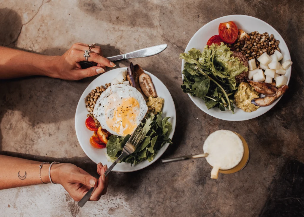 Two plates of a healthy breakfast with eggs, lentils, fresh greens and grilled sausage served at the beachfront restaurant at Talalla Retreat, Sri Lanka