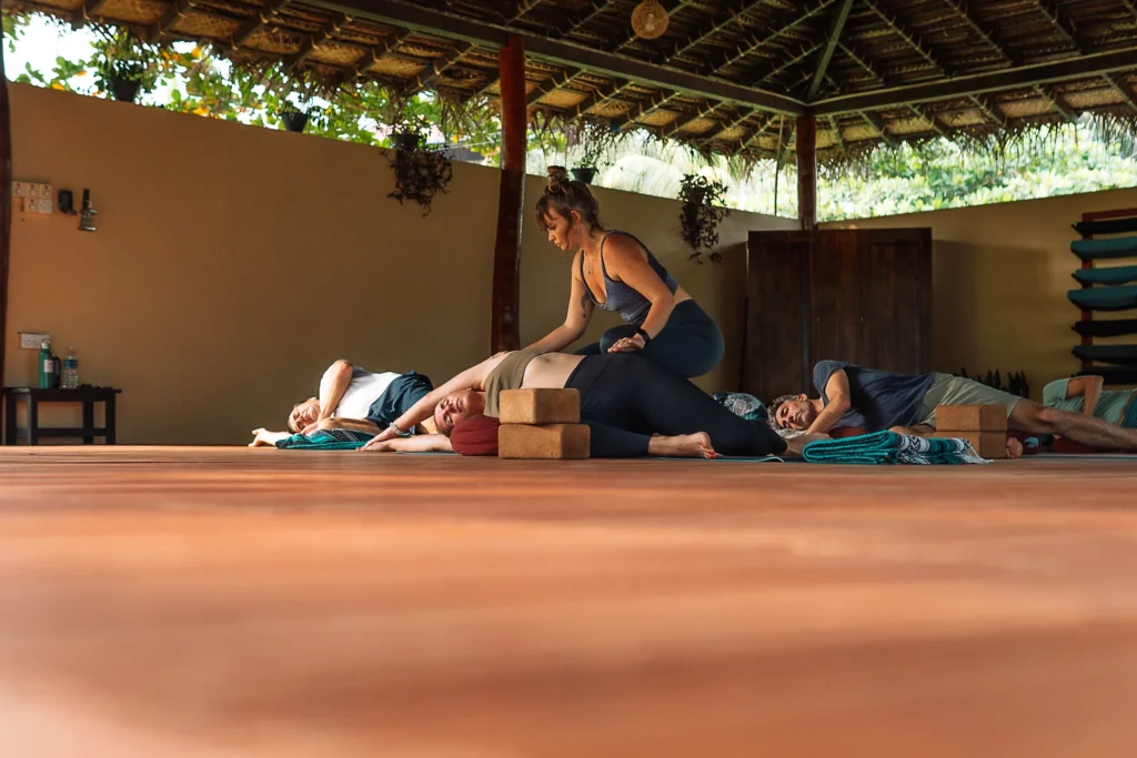 Yoga teacher guiding students through a restorative pose at a beachfront yoga retreat in Sri Lanka, Talalla Retreat