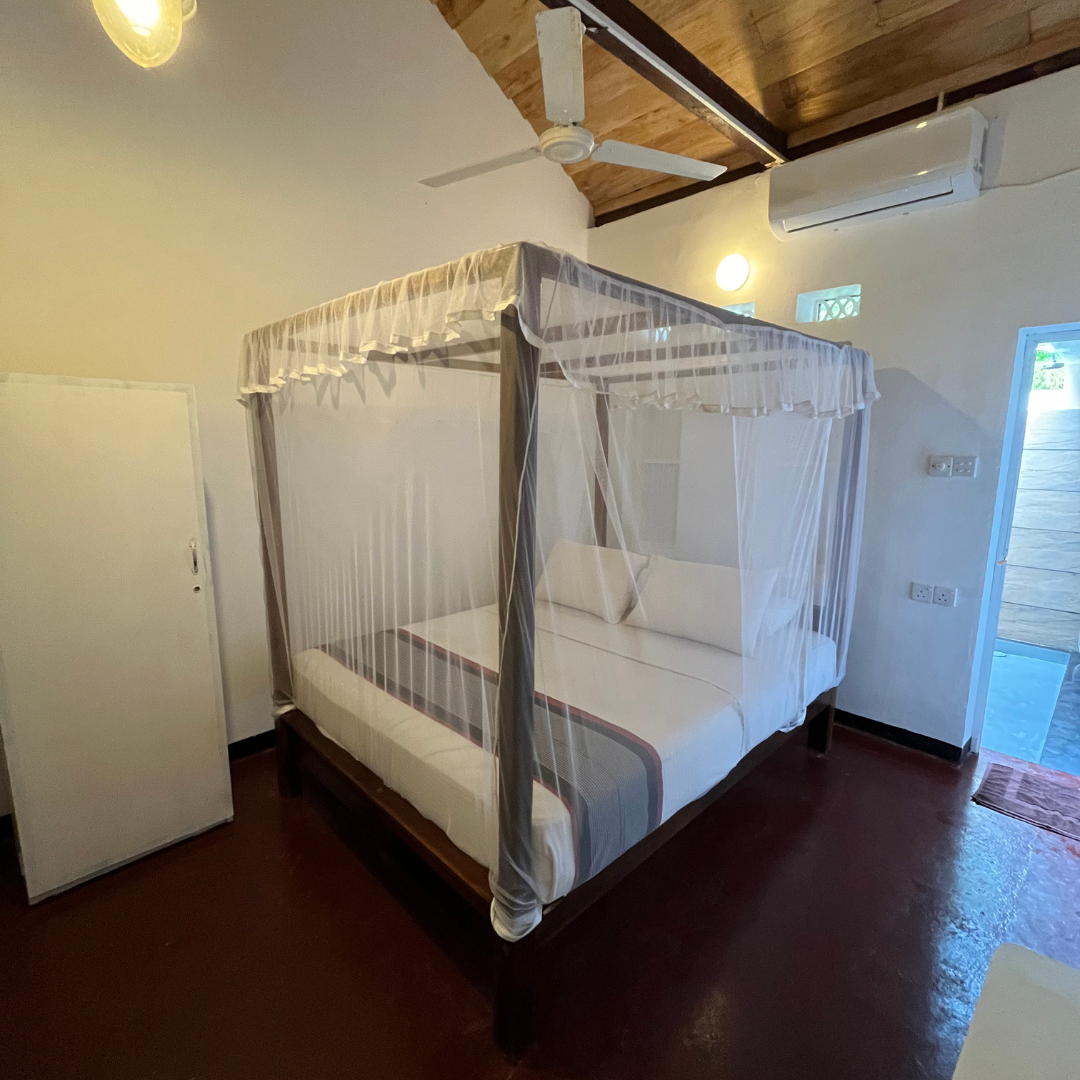 Bungalow room with a four-poster bed and mosquito netting at Talalla Retreat, Sri Lanka