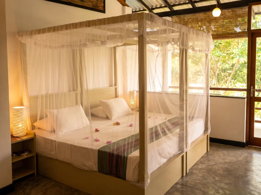 Canopy bed in a guest room opening onto a balcony at Talalla Retreat