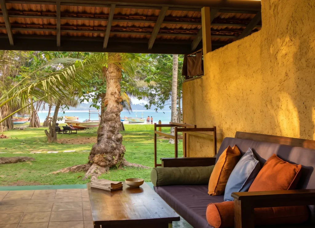 Veranda lounge looking through the palms to the ocean at Talalla Retreat