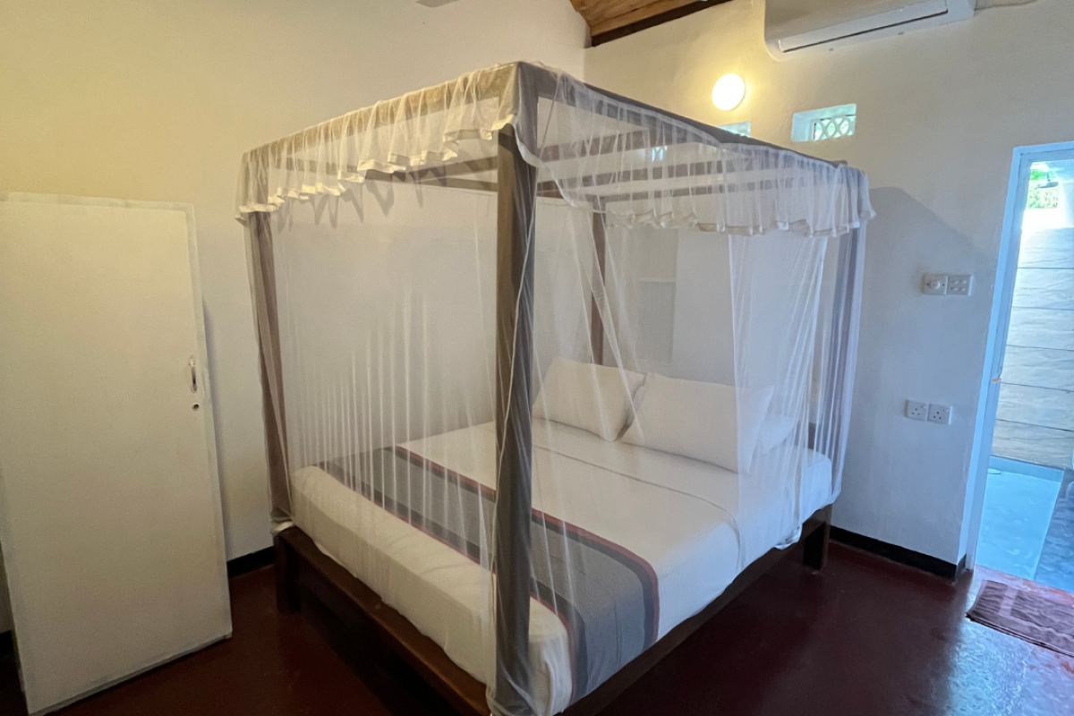 Bungalow room with a four-poster bed and mosquito netting at Talalla Retreat, Sri Lanka
