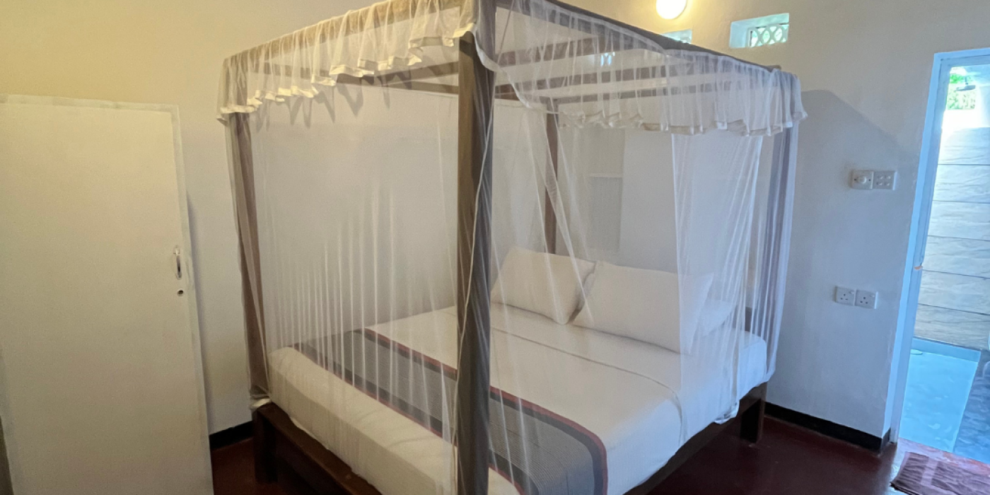 Bungalow room with a four-poster bed and mosquito netting at Talalla Retreat, Sri Lanka