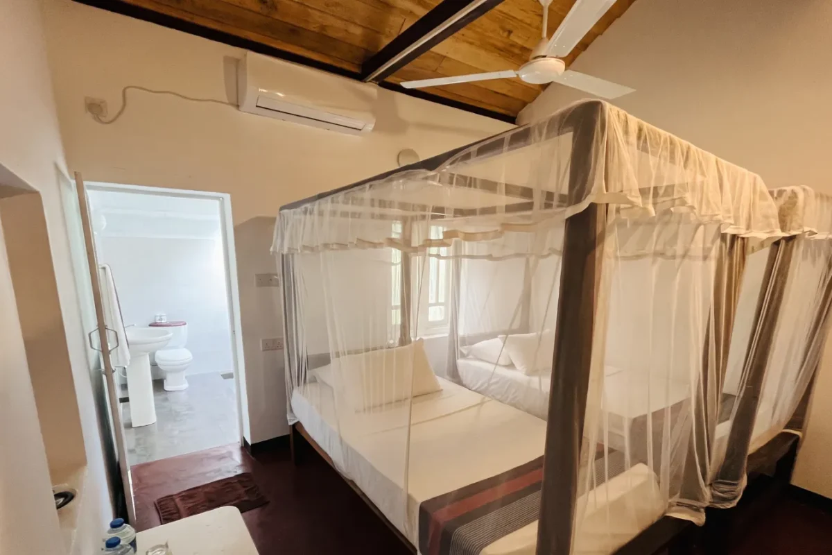 Canopy bed with mosquito net in a guest room at Talalla Retreat